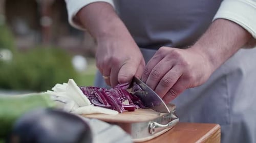 Chef Slicing Red Onion on Cutting Board