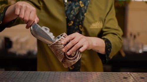 A professional bartender pours ice cubes into a shaker. The process of making cocktails in a club