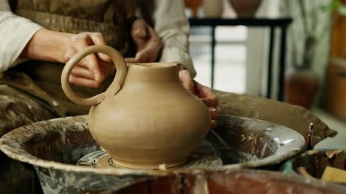 Top view of male and female hands making heart shape bowl in pottery studio molding symbol of love