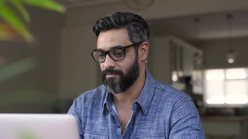 Man working on laptop from home, rubs eyes
