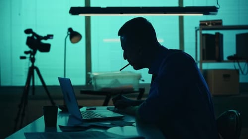 Silhouetted Man Works at Desk at Night