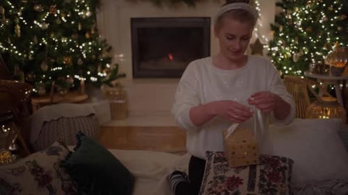 Woman Tying a Christmas Gift in Cozy Setting