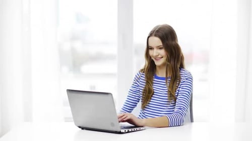 Smiling Teen Girl Using Laptop at Desk Indoors