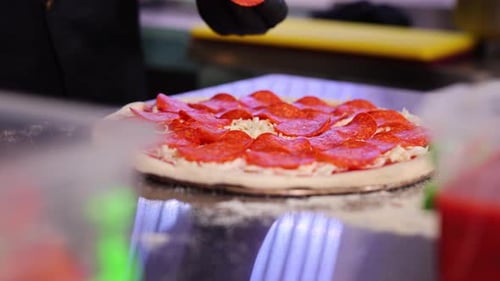 The Chef Puts Chorizo Slices on the Pizza in the Restaurant Kitchen