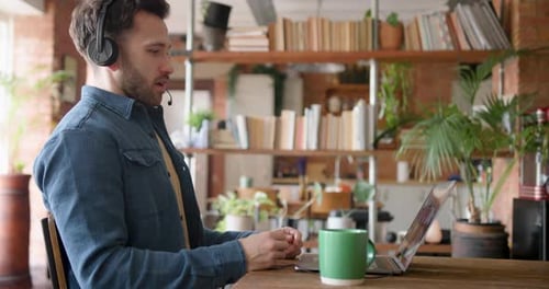 Man Video Conferencing from Home Using Laptop and Headset