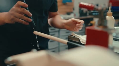 Caucasian male hands work in slow motion to pour dripping water over exposed grip on golf club shaft