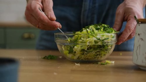 Handsome Bearded Man is Preparing Green Fresh Vegan Salad in the Kitchen at Home Male Cutting