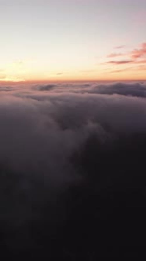Breathtaking aerial view flying over an endless sea of clouds during a beautiful golden sunset