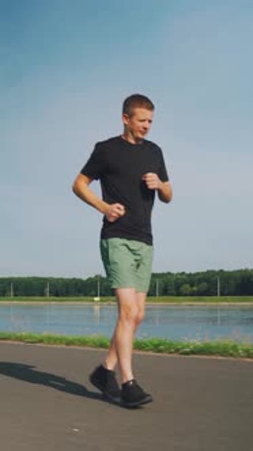 Runner Young Man Runs in the Morning in Summer on a Running Track Along the River Runner Runs Cardio