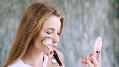 Young Woman Applying Makeup with Brush and Compact