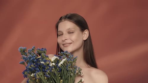 A Woman Enjoys the Aroma of Wild Flowers Inhales Their Scent Seminude Woman in the Studio on a Red
