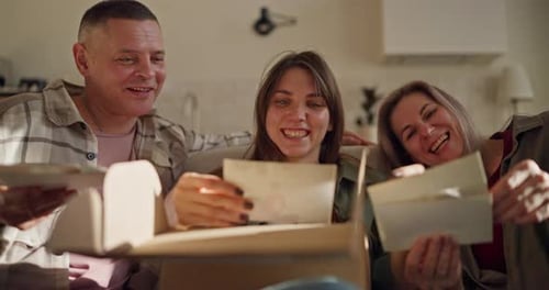 Close Up of a Happy Brunette Girl with Her Mature Parents Looking at Old Photos and Chatting on the