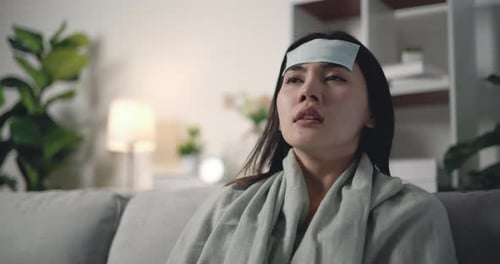 Une jeune femme asiatique malade dans une couverture chaude frissonne de froid avec du gel rafraîchissant