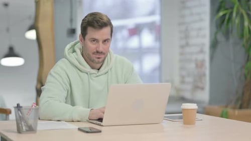 Man Working on Laptop Gives Thumbs Up