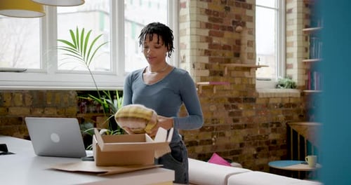 Woman Packs Sweater into Box at Home