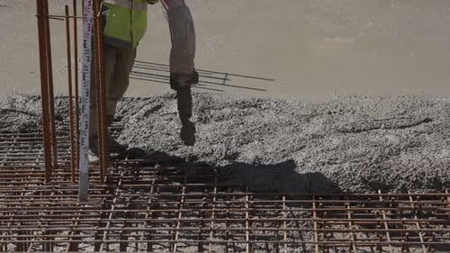 Bauarbeiter gießt flüssigen Beton über Bewehrungsgitter