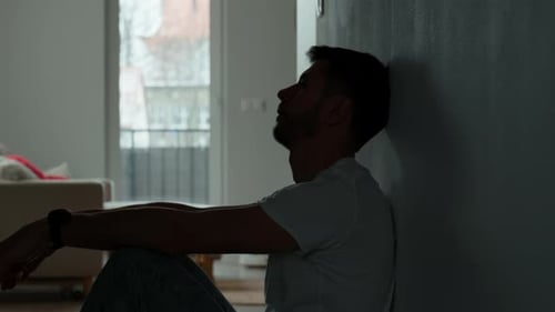 Sad Man Sitting Alone Against Wall