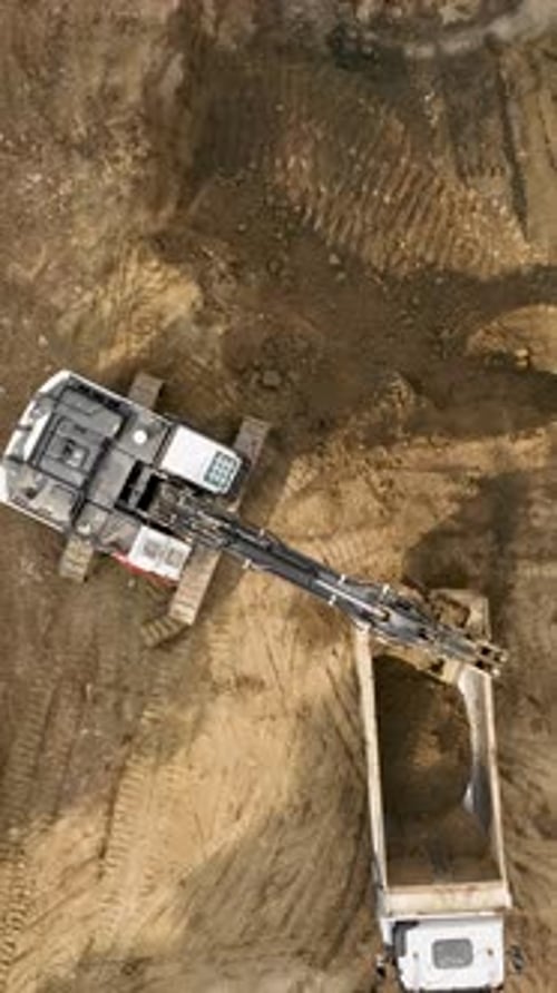 Excavator Filling Truck Bed in Rural Setting