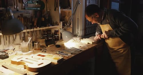 Luthier violin maker artisan carving maple wood plate for crafting violin belly in workshop
