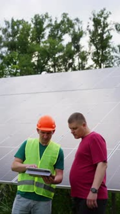 Against the Backdrop of Solar Panels an Engineer Explains to the Client
