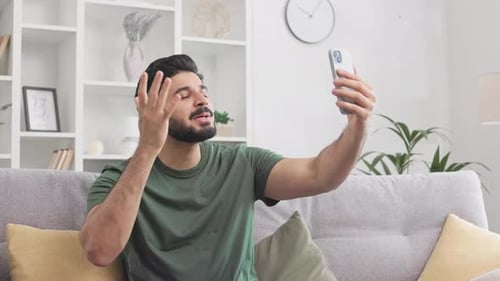 Young Adult Man Video Chatting on Smartphone at Home