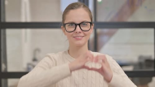 Woman Making Heart Shape with Hands and Smiling