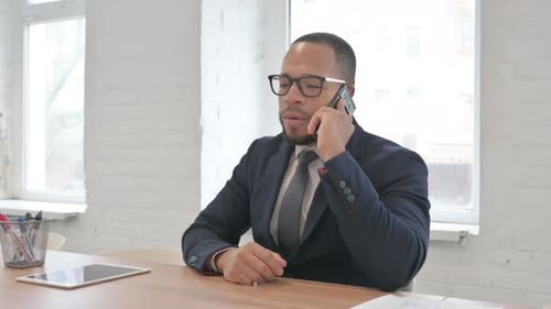 Mixed Race Businessman Talking on phone in Office