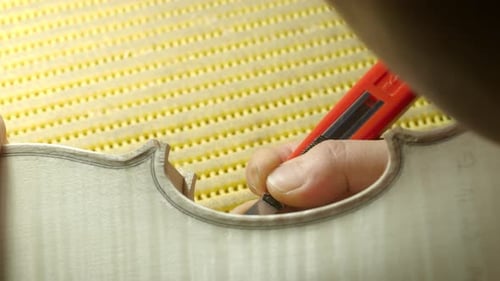 Luthier cutting purfling channel on spruce violin top plate using precision utility knife