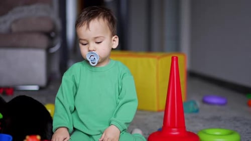 Calm lovely baby sitting on the carpet with toys around.