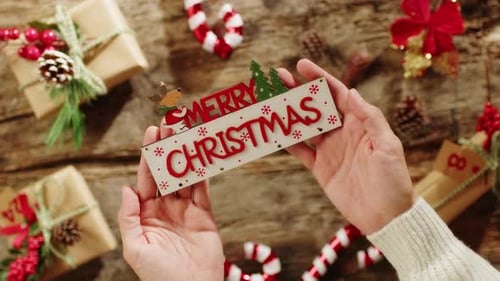 Hands Holding Christmas Decoration Above Gifts