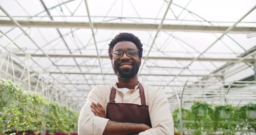 Man Smiling with Arms Crossed in Greenhouse