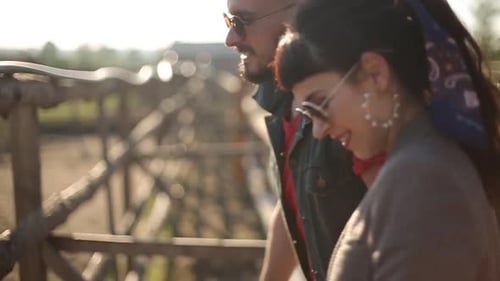 Una pareja joven acaricia un caballo blanco en el rancho una tarde soleada, un hombre acaricia un animal en un potrero