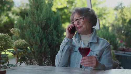 Happy Life of Successful Old Lady in Denim Shirt Having a Business Phone Call During Alcohol