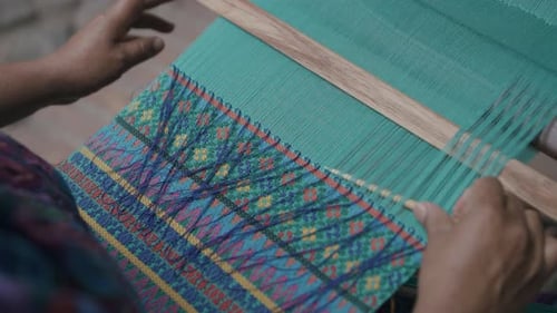 Slow motion as a woman threads a needle through a fabric in Guatemala.