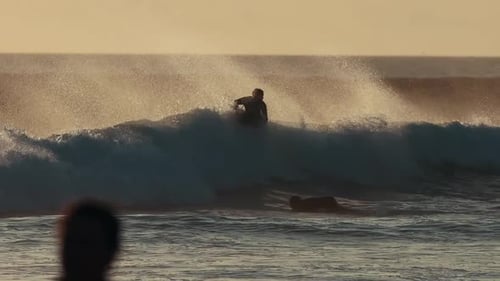 Surfer Rides Wave at Sunrise on the Beach