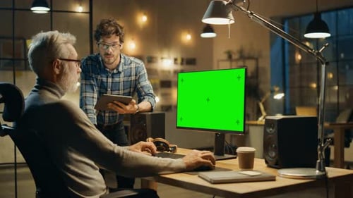 In the Evening Creative Middle Aged Man Works on a Desktop Computer Green Mock-up Screen, Has Conve