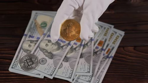Hand Holding Bitcoin Over US Currency