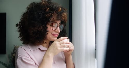 Happy Positive Woman with Curly Hair Wearing Glasses Holding Cup Enjoy Favorite Tea Drink Morning