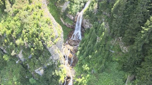 Waterfall Cascades Down Mountainside in Lush Greenery