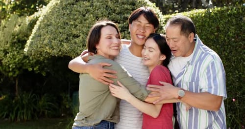 Loving Family of Four Embraces Outdoors in Sunlight