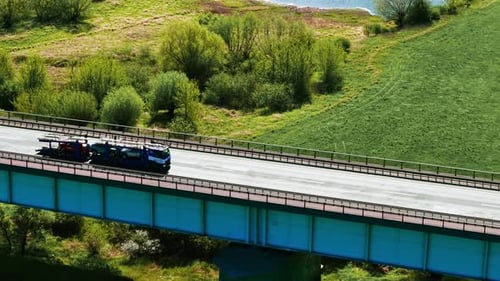 Semi Trucks with Cargo Trailer Driving By Bridge Over River Cargo Transportation and Delivery Moving