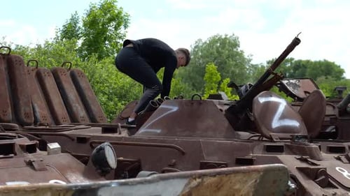 Young Adult Climbing on a Rusty Tank