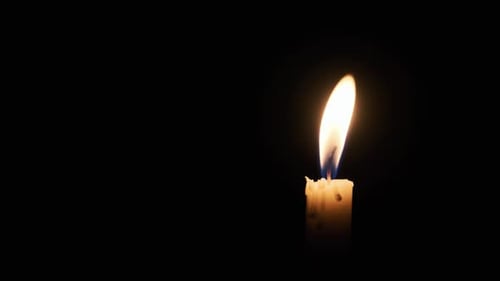 Single Candle Burns on a Black Background