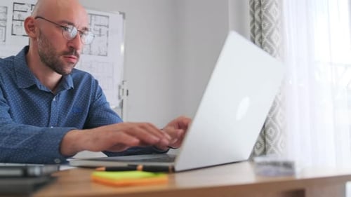 Architect Reviews Blueprints Professioneller Designer arbeitet fleißig an Bauplänen und Notizen in