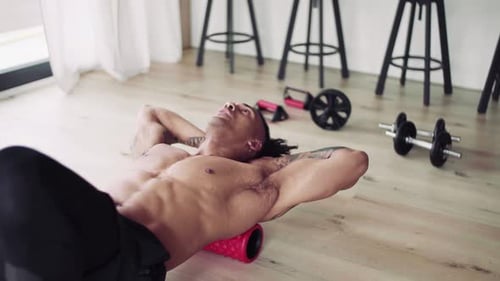 Muscular Man Using Foam Roller for Back Workout