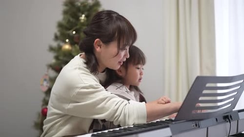 Woman Teaching Child Piano at Home Christmas Time