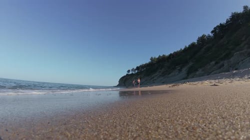 Slow Motion Video of Two Happy Shirtless Boys Running Barefoot Along a Sandy Beach Near the Sea