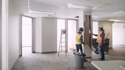 Construction Workers Demolishing Interior Office Wall