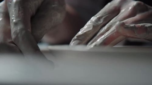 Hands in White Clay Make a Plate on a Potter's Wheel Close Up