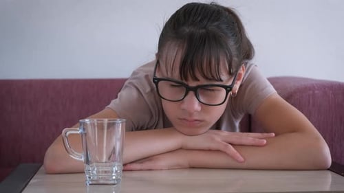 Teenage Girl with Empty Glass Resting at Table